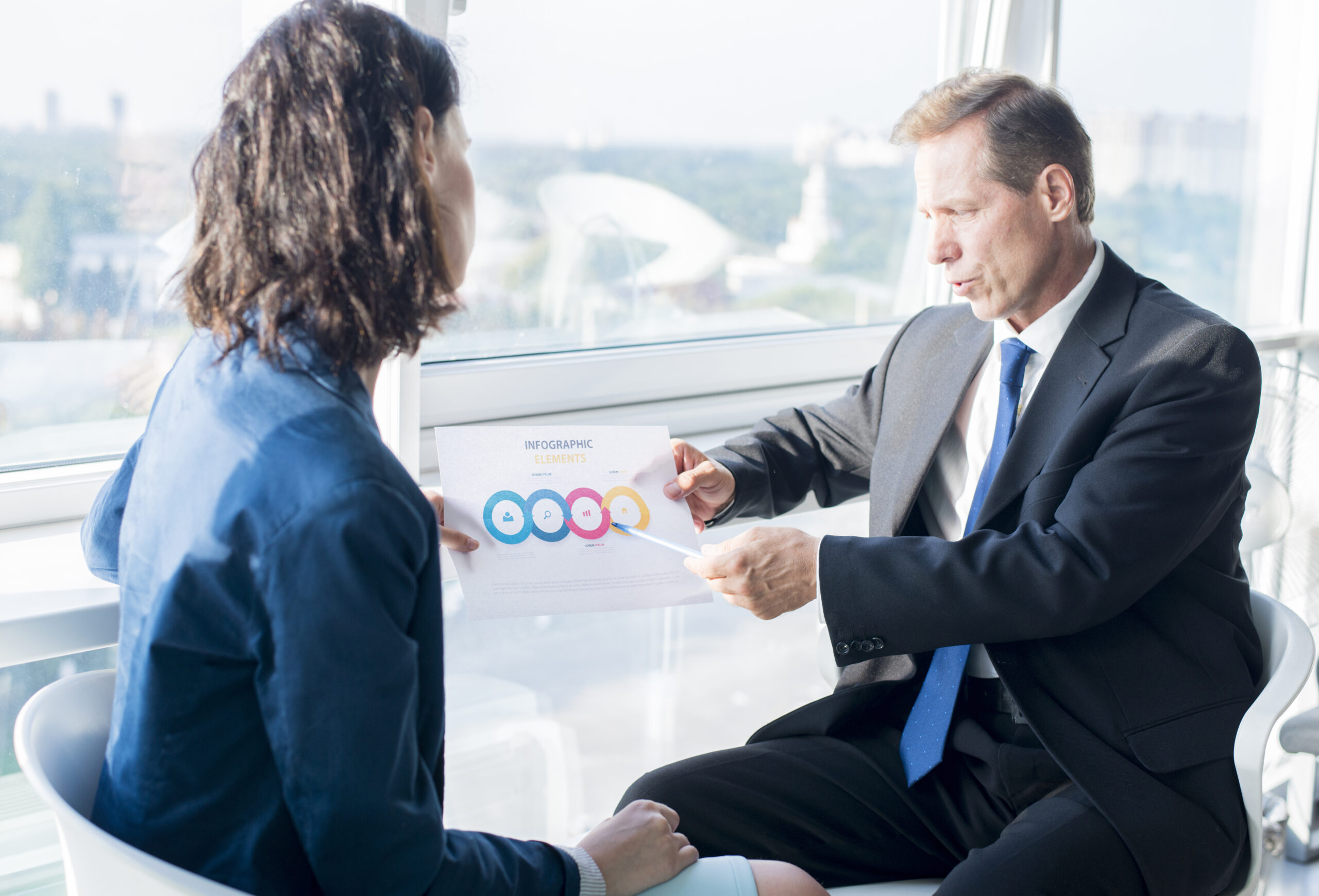 homme-affaires-expliquant-feuille-elements-infographiques-sa-collegue-feminine